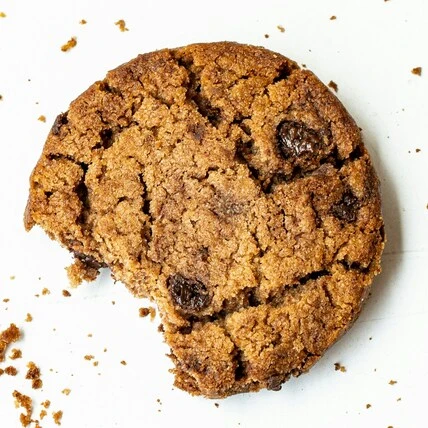 a close up image of Big pete's chocolate chip thc cookie, with crumbs around it on a white background