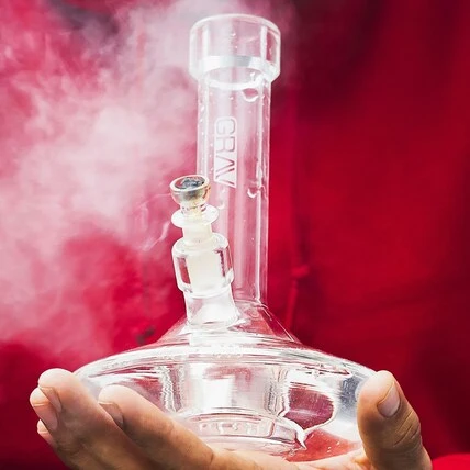 clear glass cookies original bong in a hand with smoke coming from it
