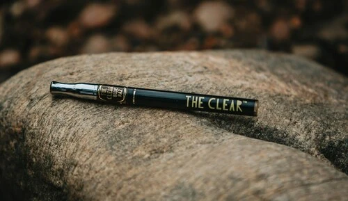 cookies cereal milk and cereal milk a la mode dual chamber disposable weed pen rested on top of a log in the woods