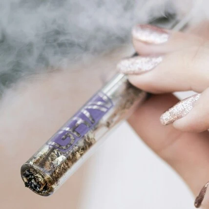 High life 4 inch glass blunt in a female hand with smoke clouds around it