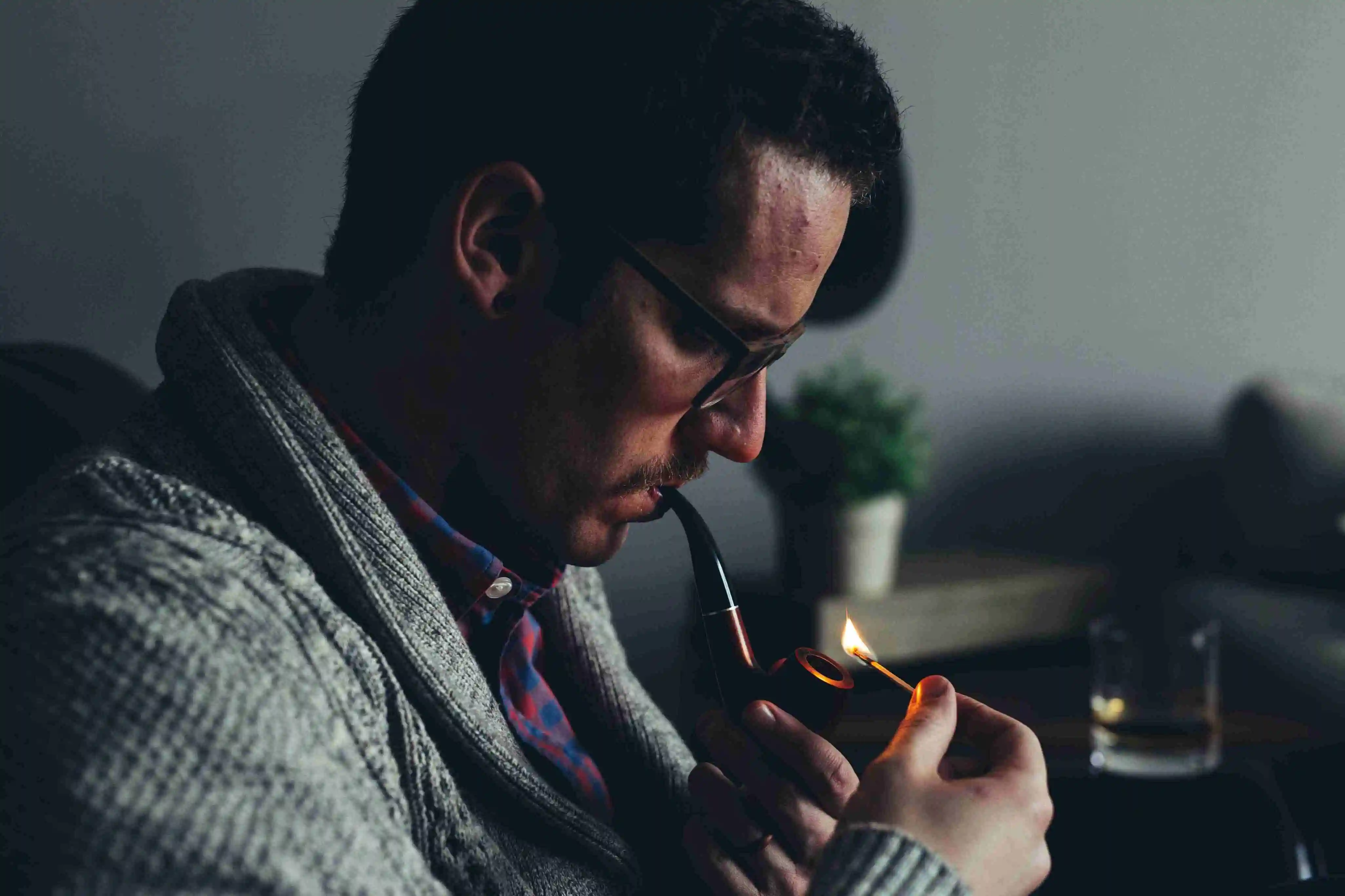 middle aged man lighting a smoking pipe with a match