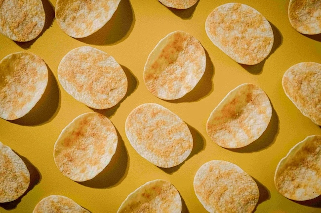 overhead picture of potato chips in a zig zag pattern against a yellow background