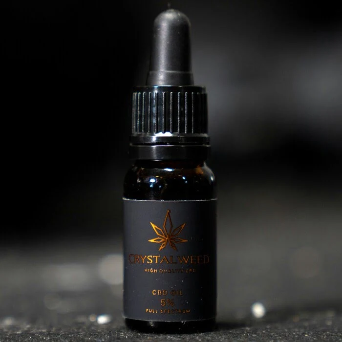 close up image of the Tweed Houndstooth Oil Spray in a bottle on a black background.