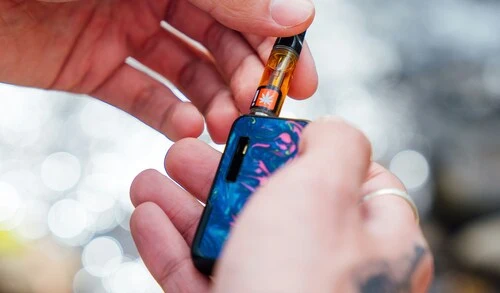 cookies gary payton 1g vape cartridge getting placed in a multicolor vape battery